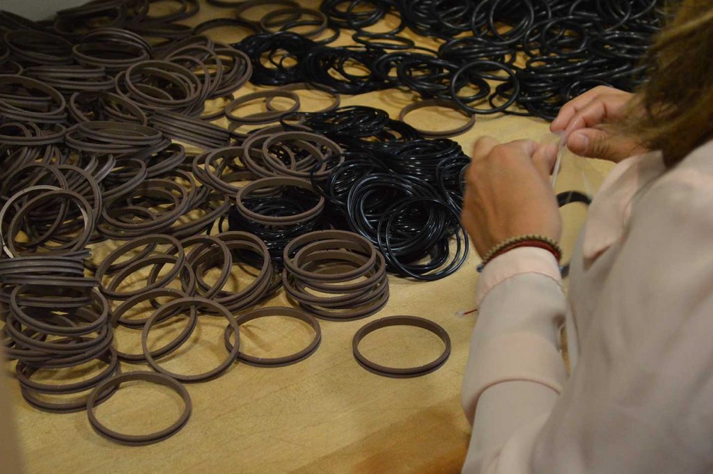 grouping of many imperial seals in brown and black with woman's hands packaging them - spring energized seal